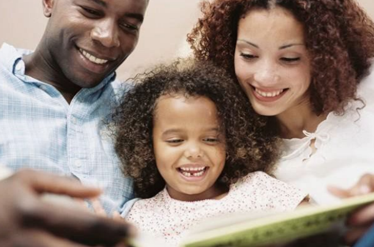  image of two adults reading to child with book 